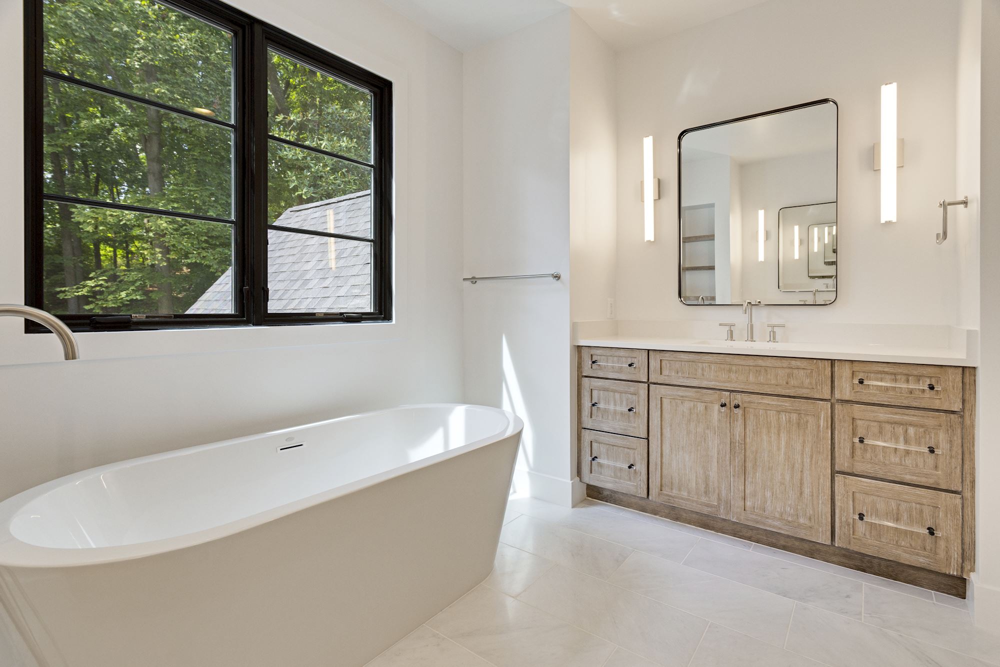 Soaking tub under a black-framed window. Morning light, no audience.